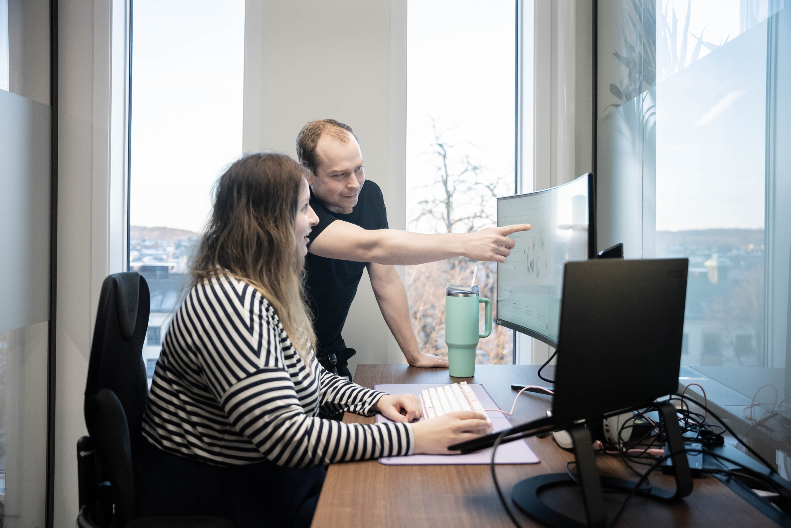 To Uniweb-medarbeidere i et kontormiljø arbeider med domeneadministrasjon og teknisk support for å hjelpe kunder med deres digitale tilstedeværelse.